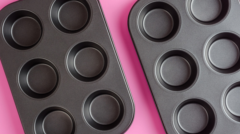 Empty muffin tins on pink background