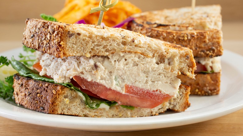 A tuna salad sandwich on a plate with toothpick in middle