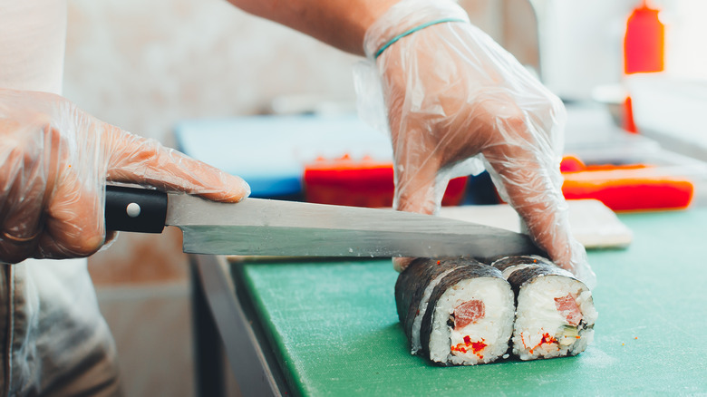 A chef using a yanigaba to slice maki from a roll