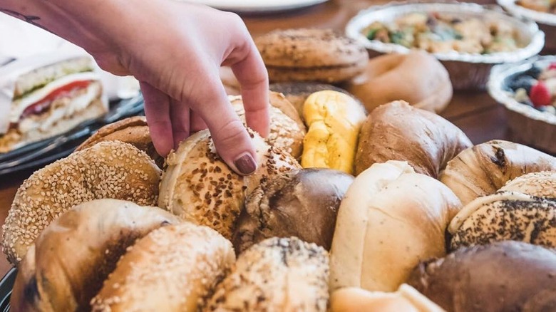 Hand choosing bagel from display