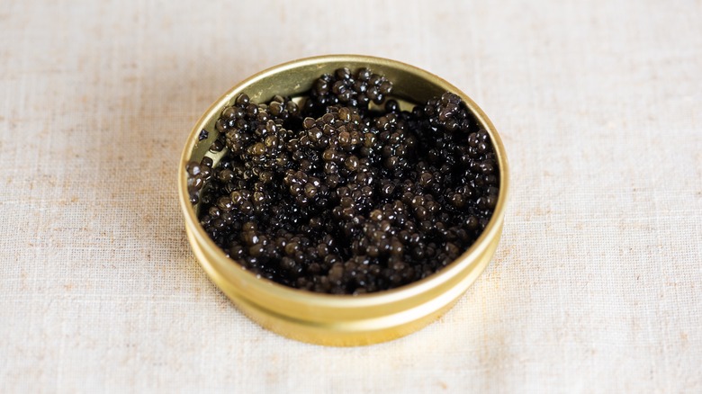 Caviar in a golden tin on a linen tablecloth