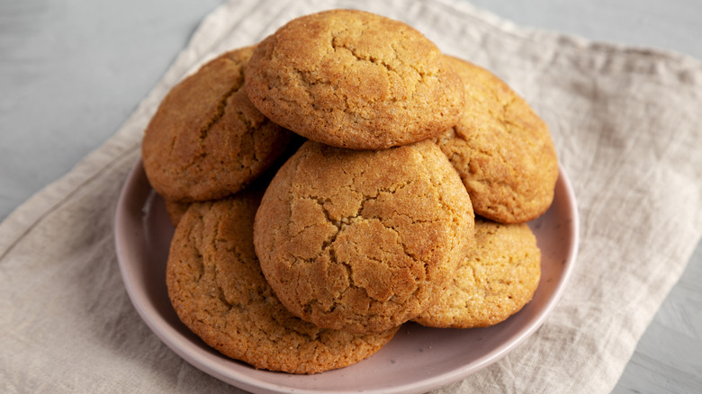 Snickerdoodle cookies are stacked on a plate, which sits on folded linen towel