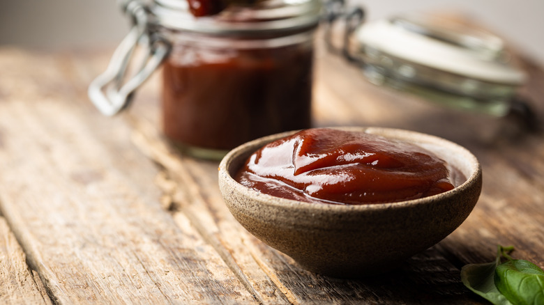 barbecue sauce in a bowl with a glass jar of barbecue sauce in the background