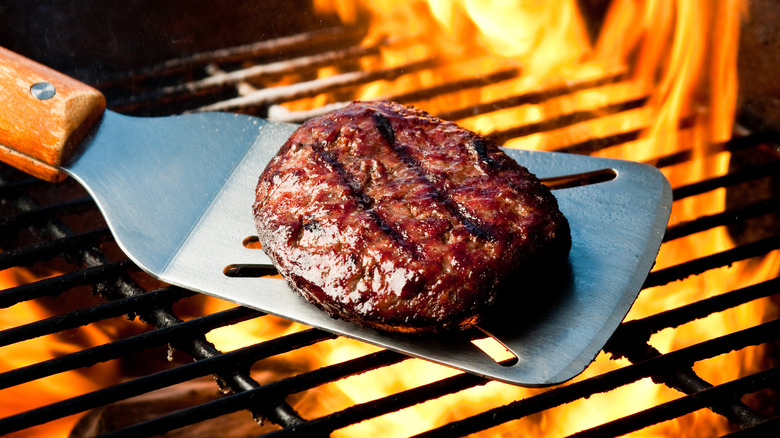 Burger on a spatula over a hot grill