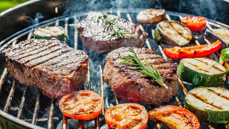 steak and vegetables being cooked on the grill