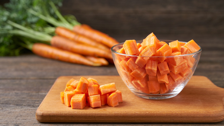 Chopped carrots in a bowl on a cutting board