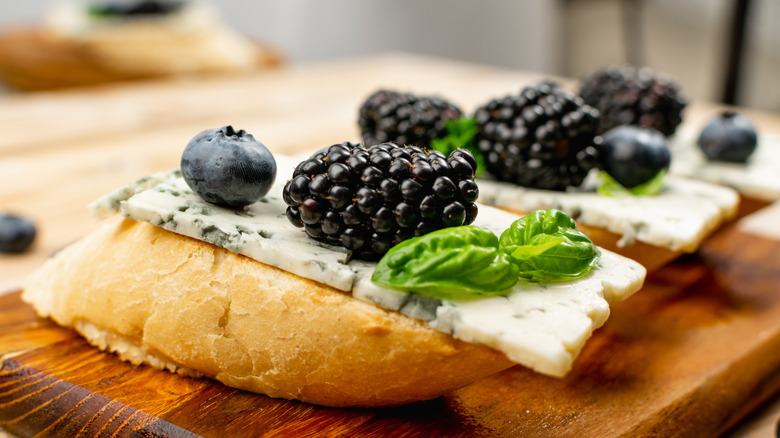 a piece of bread with blue cheese, blueberries, and blackberries