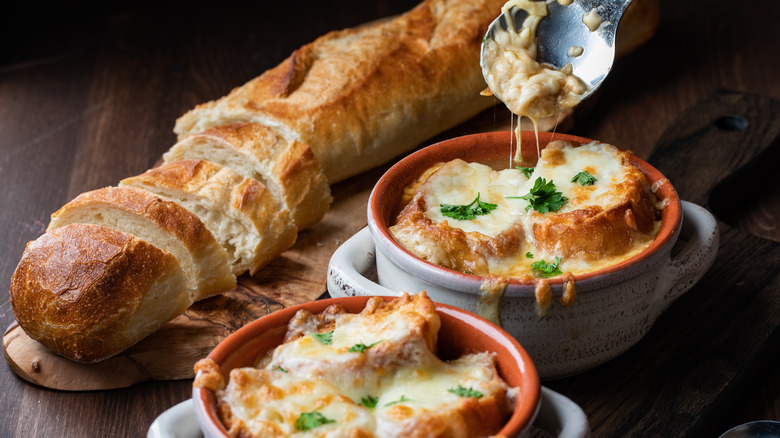 Two crocks of French onion soup with baguette on side