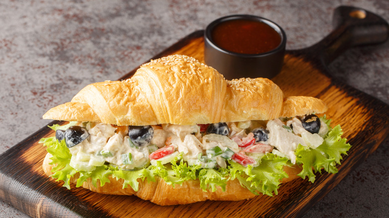 A big croissant with a creamy chicken salad that has extra vegetables