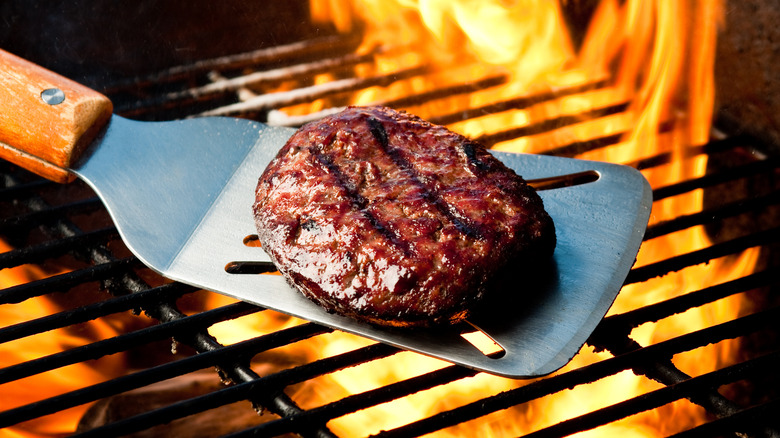 Juicy burger patty on a fiery grill