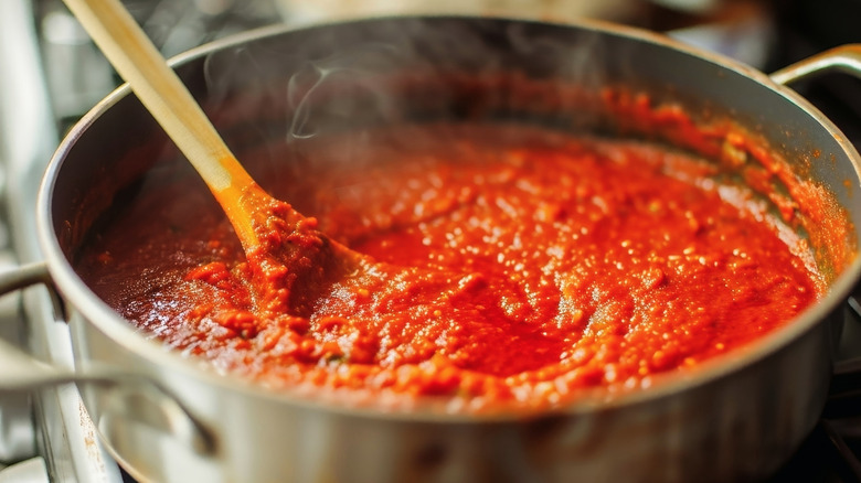 A wooden spoon stirring a savory tomato sauce