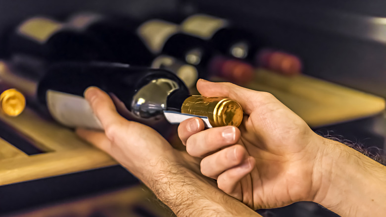 A waiter removing a bottle of wine from storage