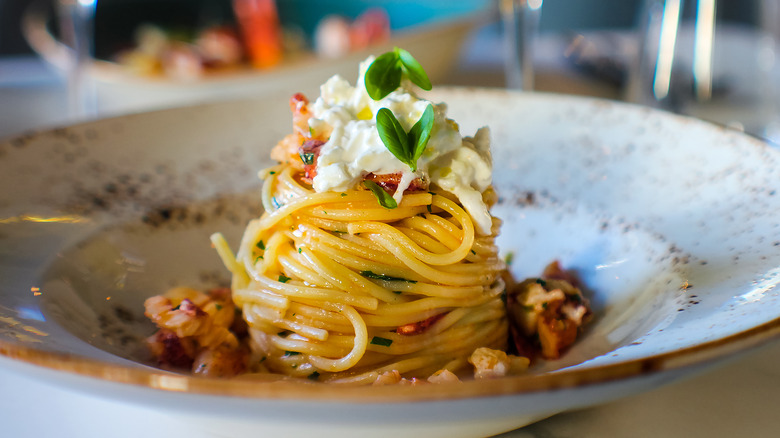 spaghetti twirled high in a shallow bowl topped with ricotta