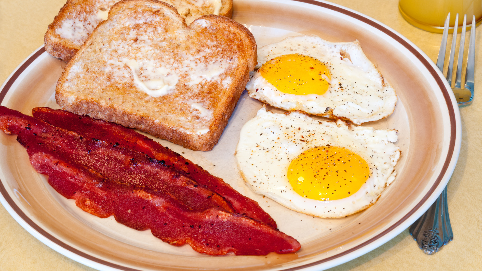 a-breakfast-sandwich-on-a-metal-plate-with-strawberries-on-the-side