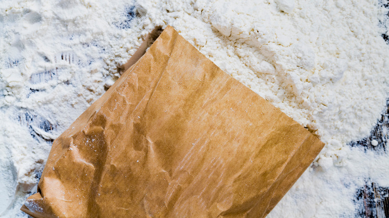 Folded brown paper bag on top of floured surface