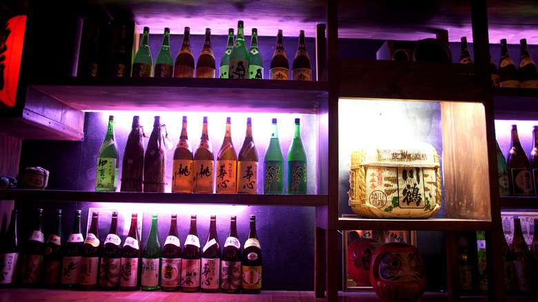 Backlit bottles of sake lined on shelves in a club