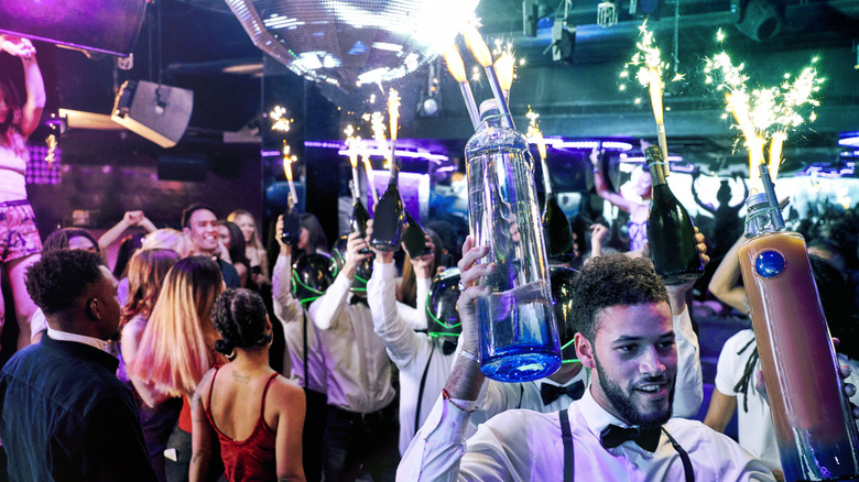 Bottle service waiters carrying sparklers and bottles of liquor