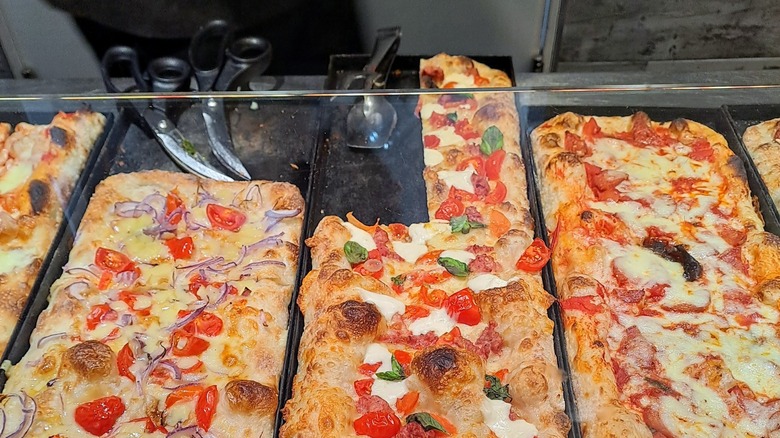 trays of pizza al taglio with different toppings