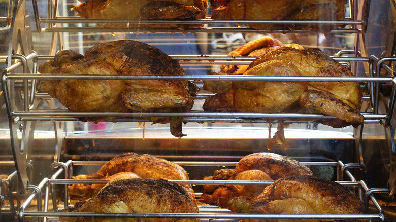 Rotisserie chickens on spits inside store