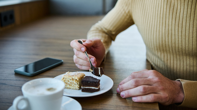 man eating dessert with cell phone on the table