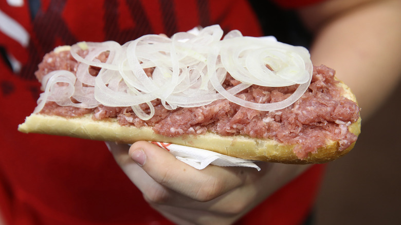 A close-up shot of a person holding an open-faced German Mett