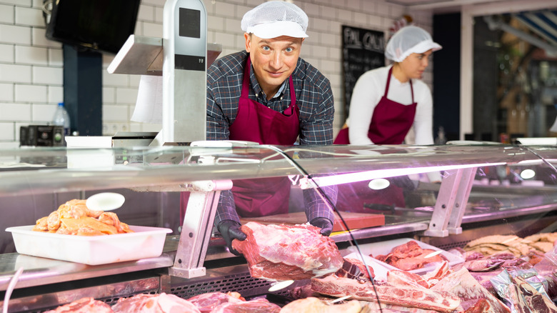 A butcher getting meat out of a case