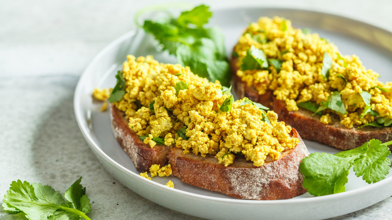 tofu scramble on thick slices of toast, topped with fresh herbs