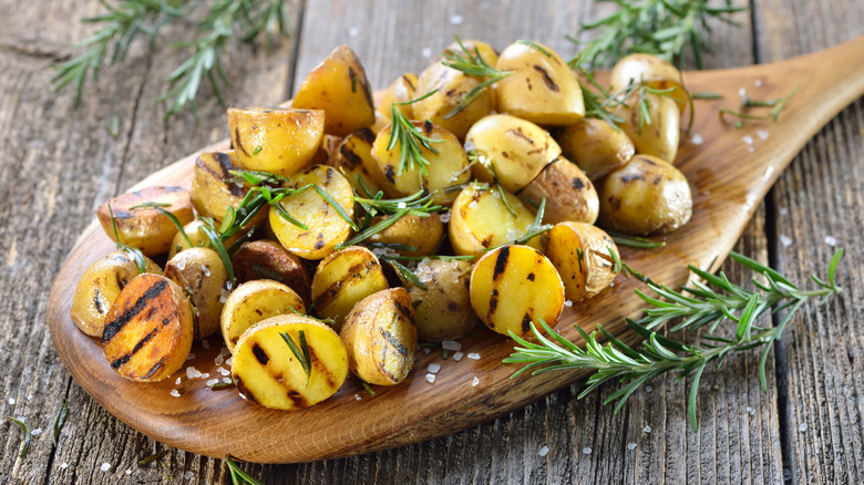 Grilled baby potatoes on board with herbs