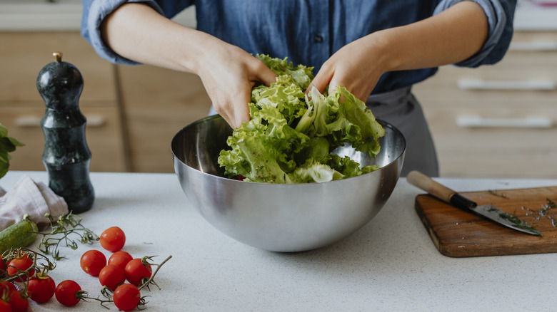 Woman's hands mixing a salad with dressing in a bowl