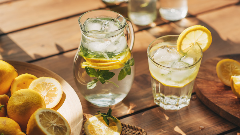 Water pitcher filled with ice, lemons, and fresh herbs.