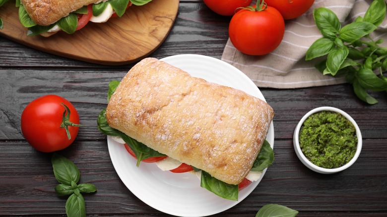 Ingredients for a tomato sandwich with pesto, mozzarella, and basil