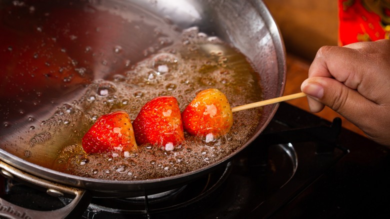 Person dipping tanghulu in sugar