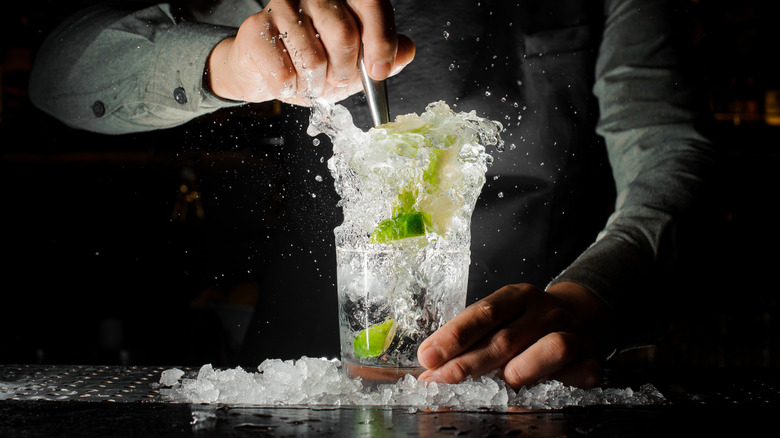 Bartender muddling overflowing vodka soda with lime