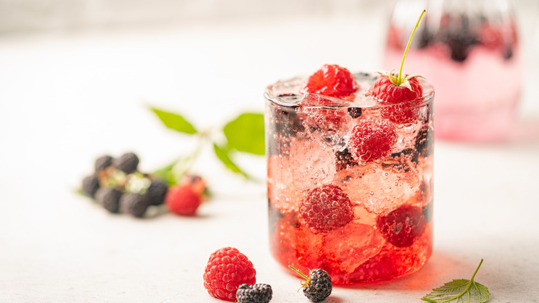 Vodka soda in glass with fresh raspberries and blackberries