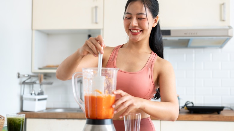 woman making smoothie in kitchen