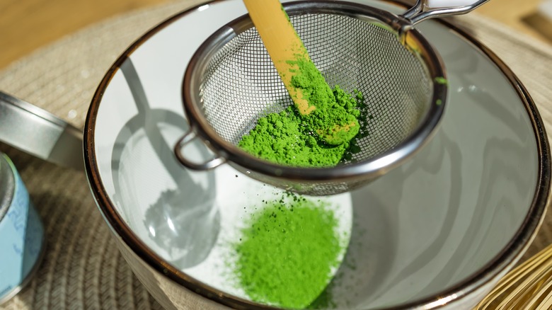 Matcha powder sifting into bowl through mesh sieve