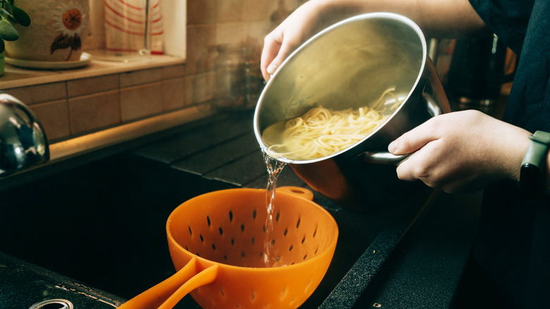 Chef pouring pasta water into a strainer