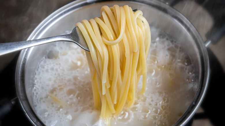 fork lifting pasta from boiling water