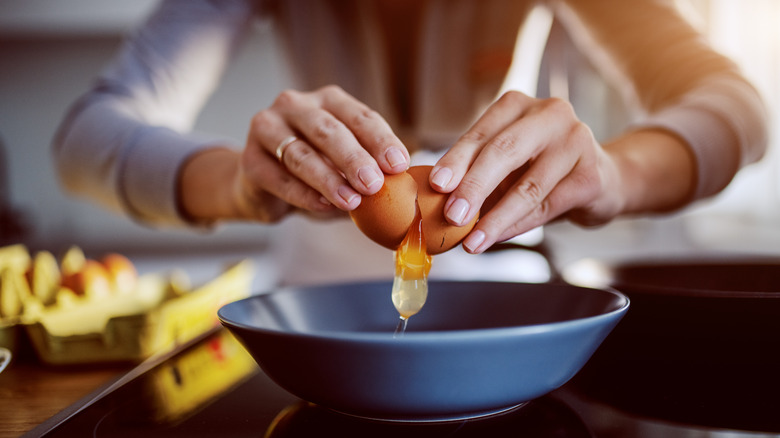 Hands cracking an egg into a bowl