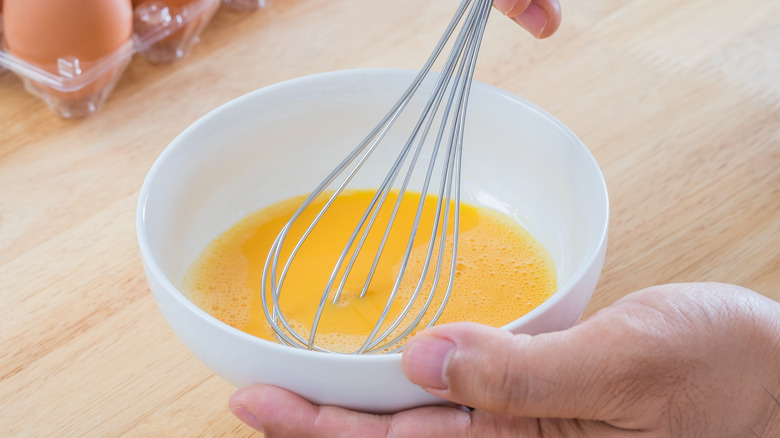 person whisking eggs in a bowl