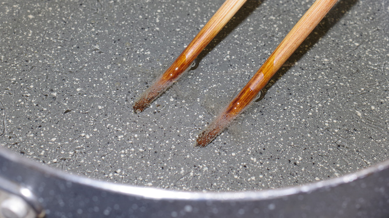 Bubbles of hot oil around wooden chopsticks