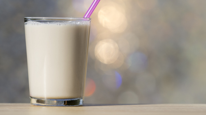 A clear glass of milk with a pink straw