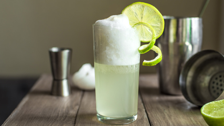 Gin fizz cocktail with limes and egg foam with shaker