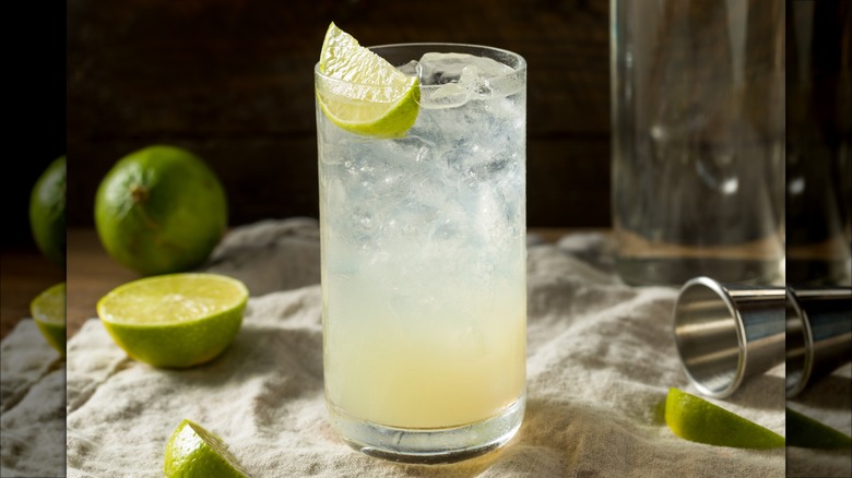 Gin Rickey cocktail on tablecloth with limes