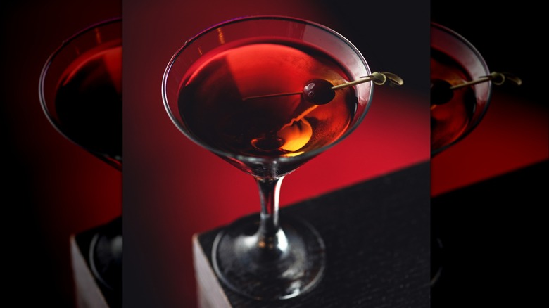 Manhattan cocktail with cherry on red background