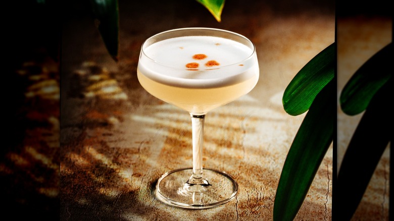 Pisco sour cocktail with drops of orange bitters on table