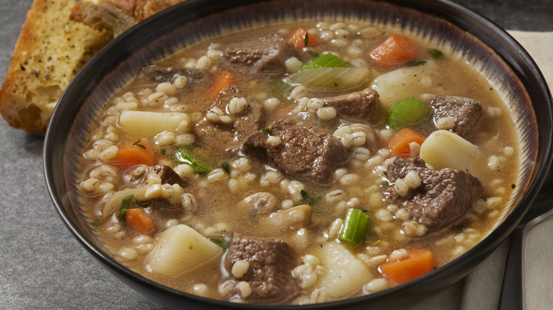 beef, potato, and barley soup in a brown bowl