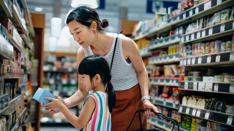 A woman and young girl shopping in a grocery store aisle