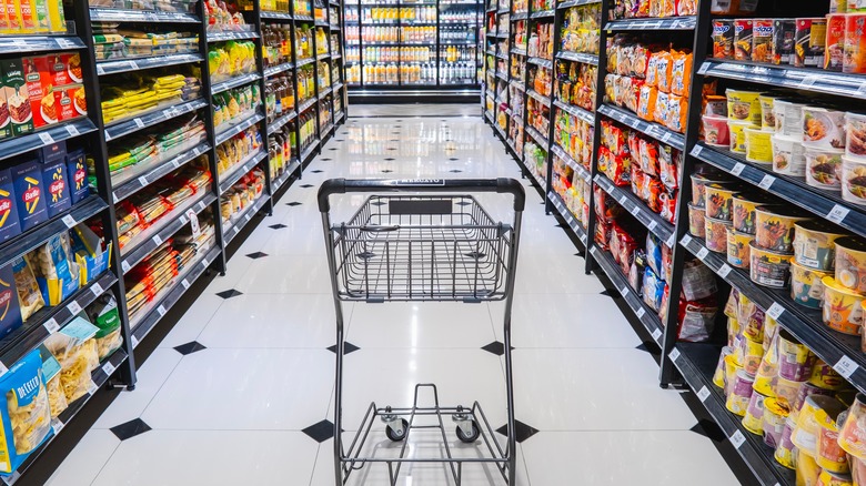 A grocery cart in the middle of a paste and noodle aisle