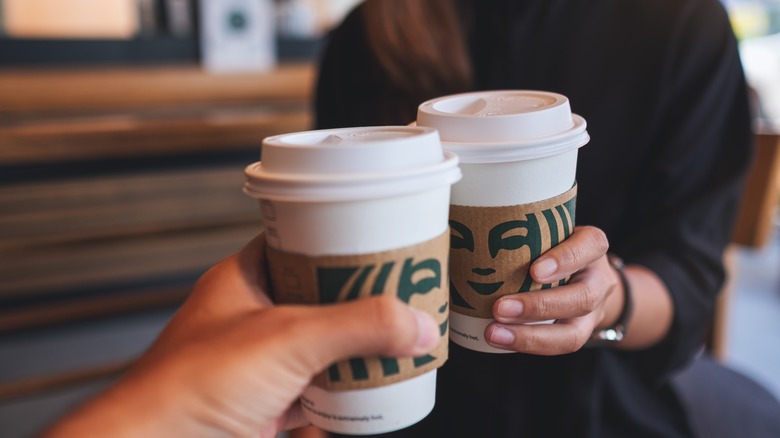 two people holding short Starbucks cups